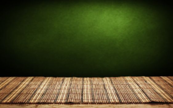 Empty bamboo table and green wall in background. 