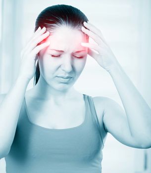 A young woman with headache holding head, monochrome photo with red as a symbol for the hardening