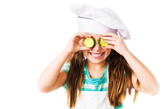 little girl in chef hat with cucumber slices on the eyes on a white background