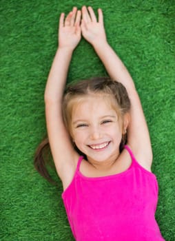 Little cute girl lying on green grass