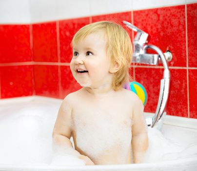 smiling little baby is taking a shower