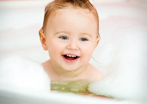 little smiling baby in a bubble bath