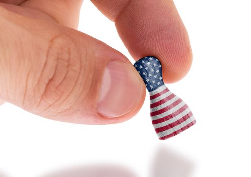 Hand holding wooden pawn with a flag painting, selective focus, United States of America