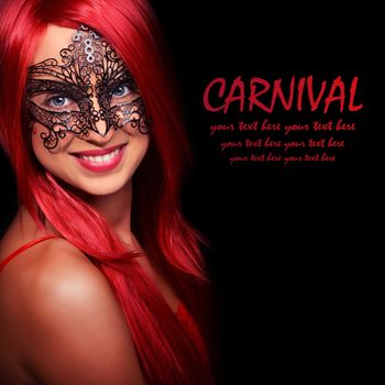 Beautiful red haired woman in carnival mask over black background