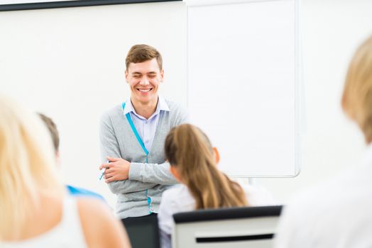 young teacher man talking with students in the classroom