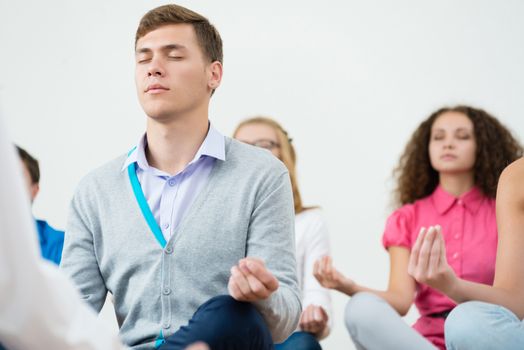 group of young people meditating in office at desk, group meditation