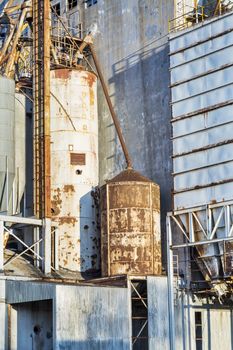 industrial background - exterior of old abandoned grain elevator with pipes, ducts, ladders and chutes