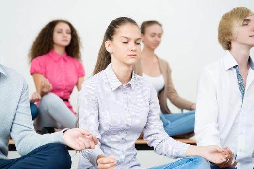 group of young people meditating in office at desk, group meditation