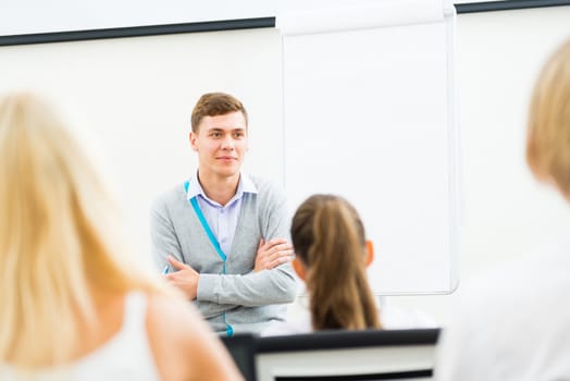 young teacher man talking with students in the classroom