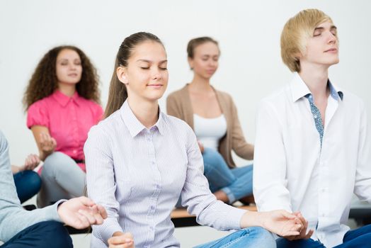 group of young people meditating in office at desk, group meditation