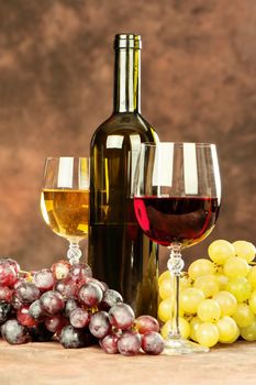 cup of a red wine in front of grape, bottle and glass of white wine