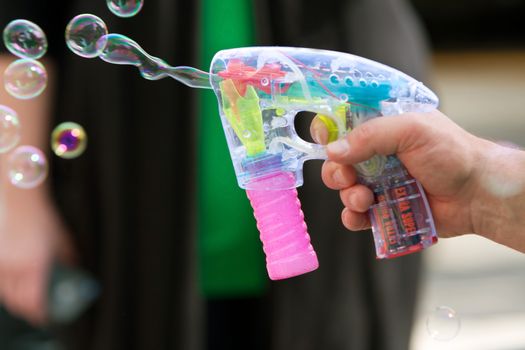 Atlanta, GA, USA - March 15, 2014:  A man's hand uses a bubble gun to blow bubbles at the St. Patrick's Day parade on Peachtree Street.