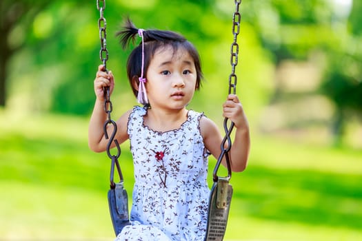 Adorable girl plays on the swing