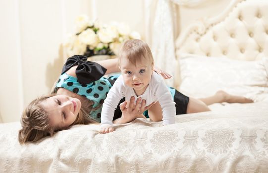 Young Caucasian mother and baby son on bed at home