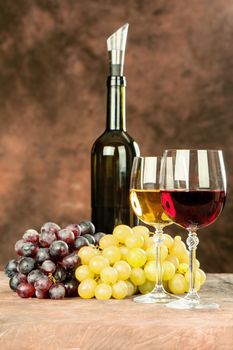 Wine bottle near shiny wine cups and grape