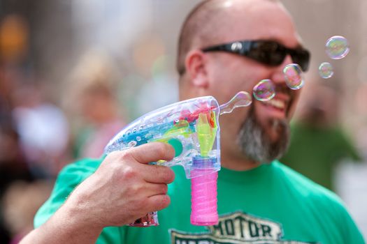 Atlanta, GA, USA - March 15, 2014:  A man uses a bubble gun to blow bubbles at the St. Patrick's Day parade on Peachtree Street. 