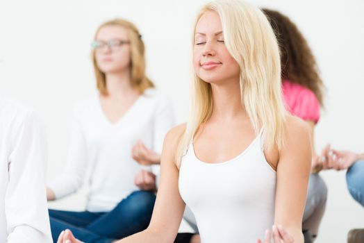 portrait of an attractive young woman, meditating with closed eyes, group meditation