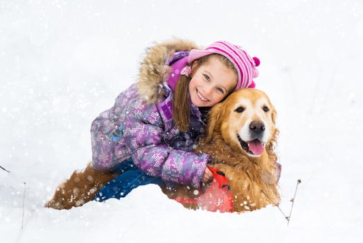 smiling little girl hugging dog in snow