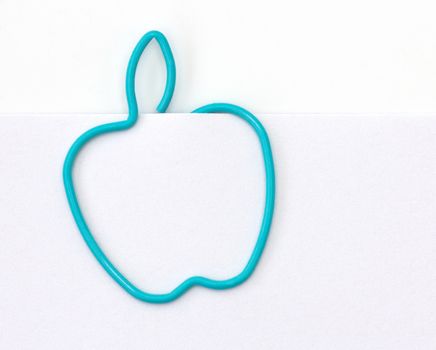 Paper clip in the form of apple on a sheet of paper