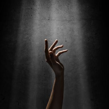 woman's hand reaches for the light rays, conceptual image of striving for freedom