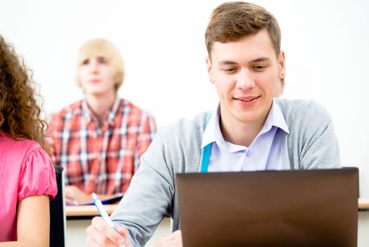 Portrait of a young student in the classroom, working with a laptop