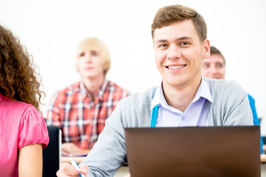 Portrait of a young student in the classroom, working with a laptop