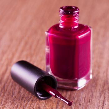 Red nail polish over a wooden background