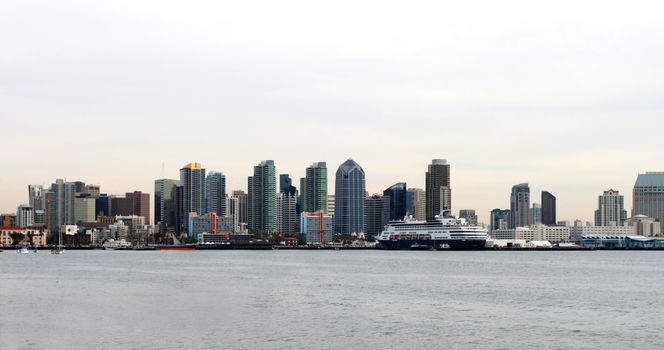 The skyline of San Diego with water in the front and cloudy sky.