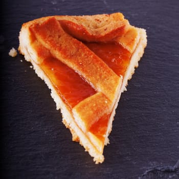 Apricot jam crostata cake over black stone background