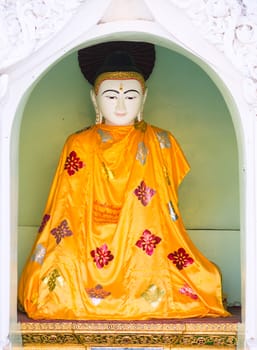 Buddha image with an orange robe at the Shwedagon Pagoda in Yangon, the capital of Republic of the Union of Myanmar.