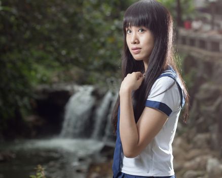 Cute Chinese schoolgirl with waterfall in background