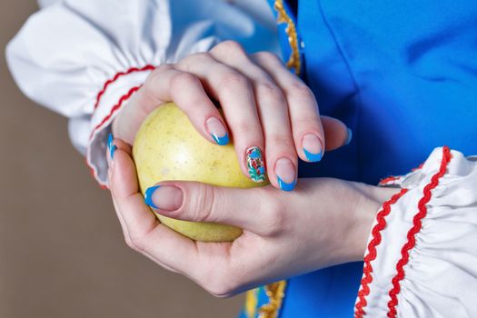 Girl holds in her hands with manicure ripe apple shot close up