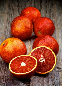 Arrangement of Ripe Full Body Blood Oranges with Two Halves isolated on Rustic Wooden background