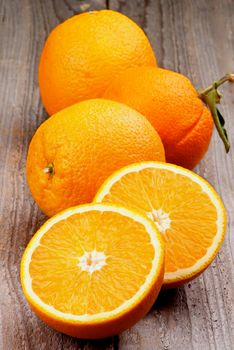 Heap of Full Body and Halves of Juicy Ripe Oranges isolated on Rustic Wooden background