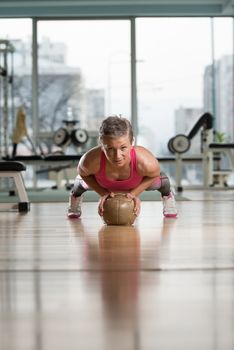 Attractive Female Athlete Performing Push-Ups On Medicine Ball