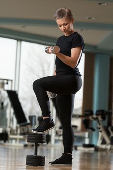 Beautiful Young Woman Working Out Biceps In A Health Club