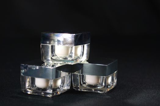 three cube acrylic cream jars, on black scene,shallow focus