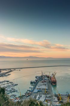 View of the busy harbor of Salerno, Italy, at sunrise with ships and containers on the dock