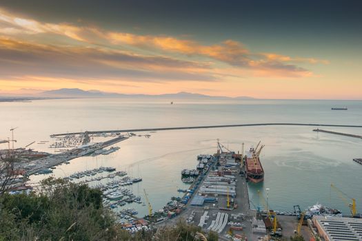 View of the busy harbor of Salerno, Italy, at sunrise with ships and containers on the dock