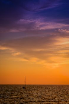 View of a sailboat at dusk, colorful sky, placid atmosphere