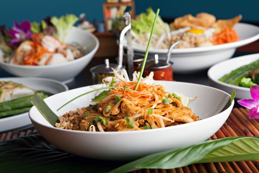 Chicken pad Thai with a variety of other fine Thai food dishes.  Shallow depth of field.