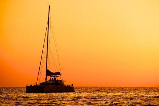 View of a catamaran sailing at sunset towards the harbour of Acciaroli, southern Italy