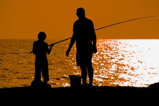 Father and son fishing at dusk silhouette