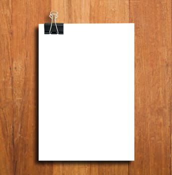 Black clip and White blank note paper hang on wood pane