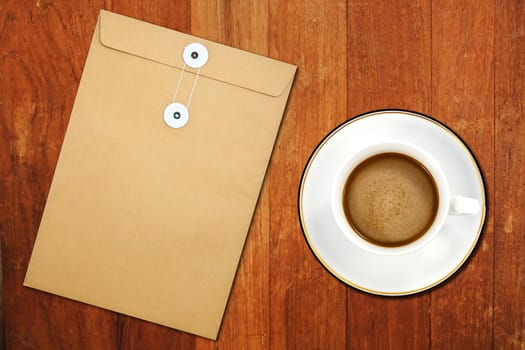 Brown Envelope document and a white coffee cup on a wooden desk