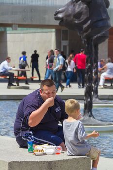 A man eating poutine with his child in Toronto city, Canada.