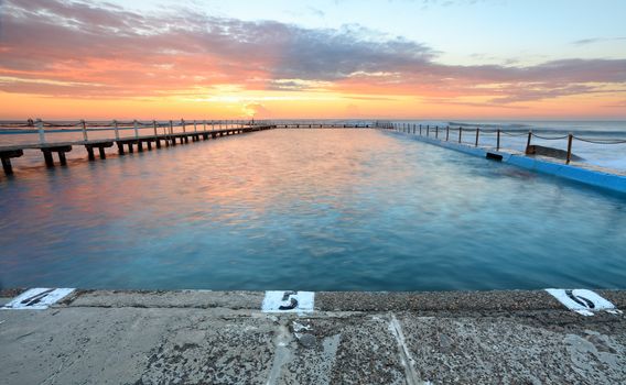 Sunrise at the ocean fed swimming pools at North Narrabeen, Australia, known as the North Narrabeen Rock Baths with its distinctive boardwalk (left) to another 50m diving platform 