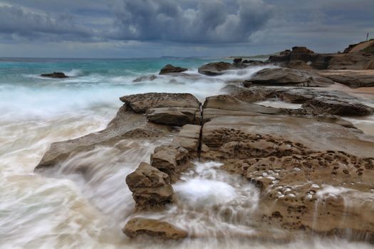 Ocean flows on rocks on a stormy afternoon.  Soldiers Beach NSW Australia