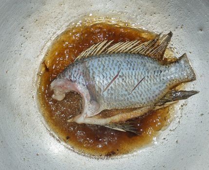 Frying tilapia on a large frying pan