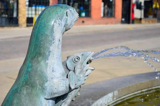 Otter holding fish statue